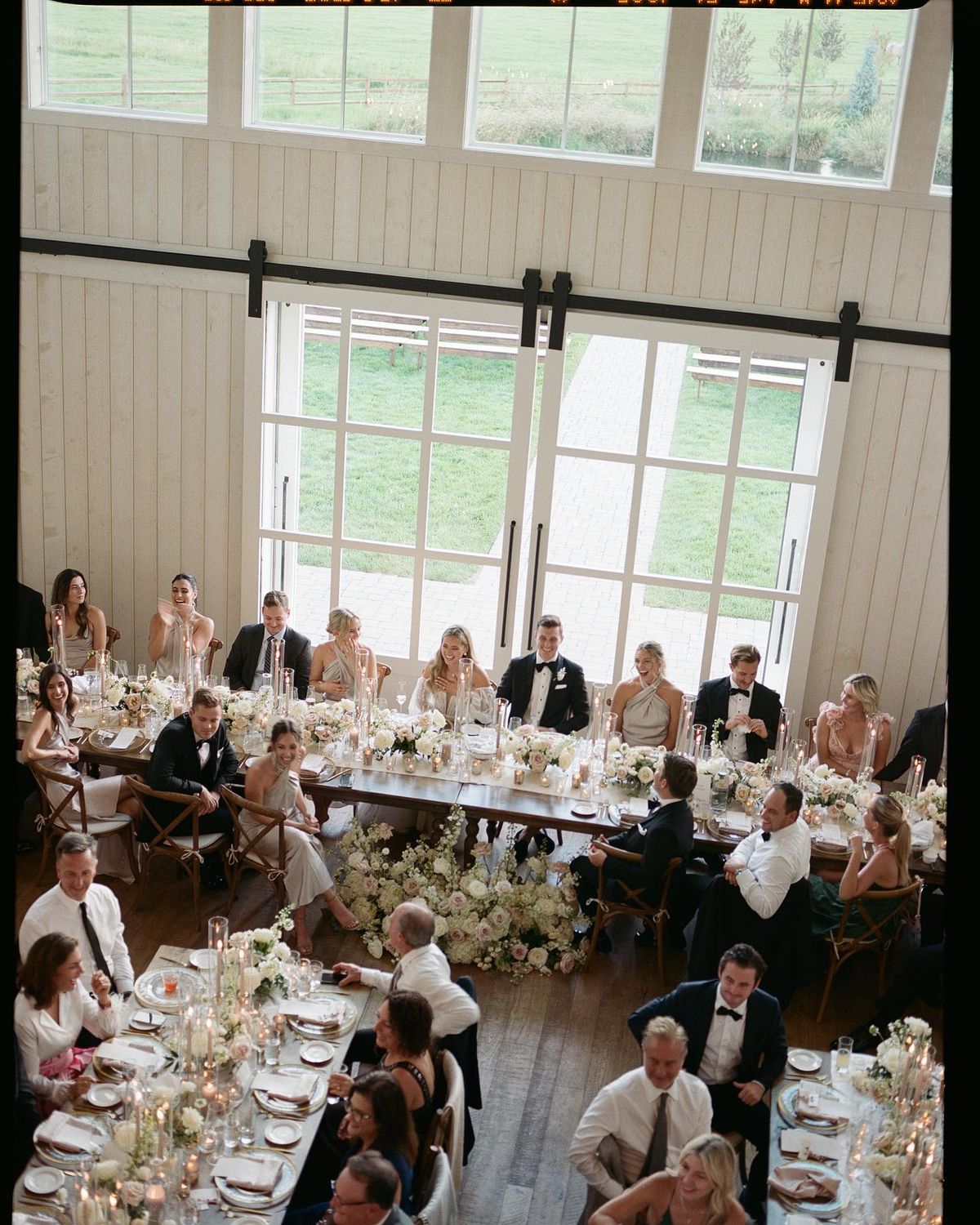 Aerial view of wedding reception head table and guest tables with florals