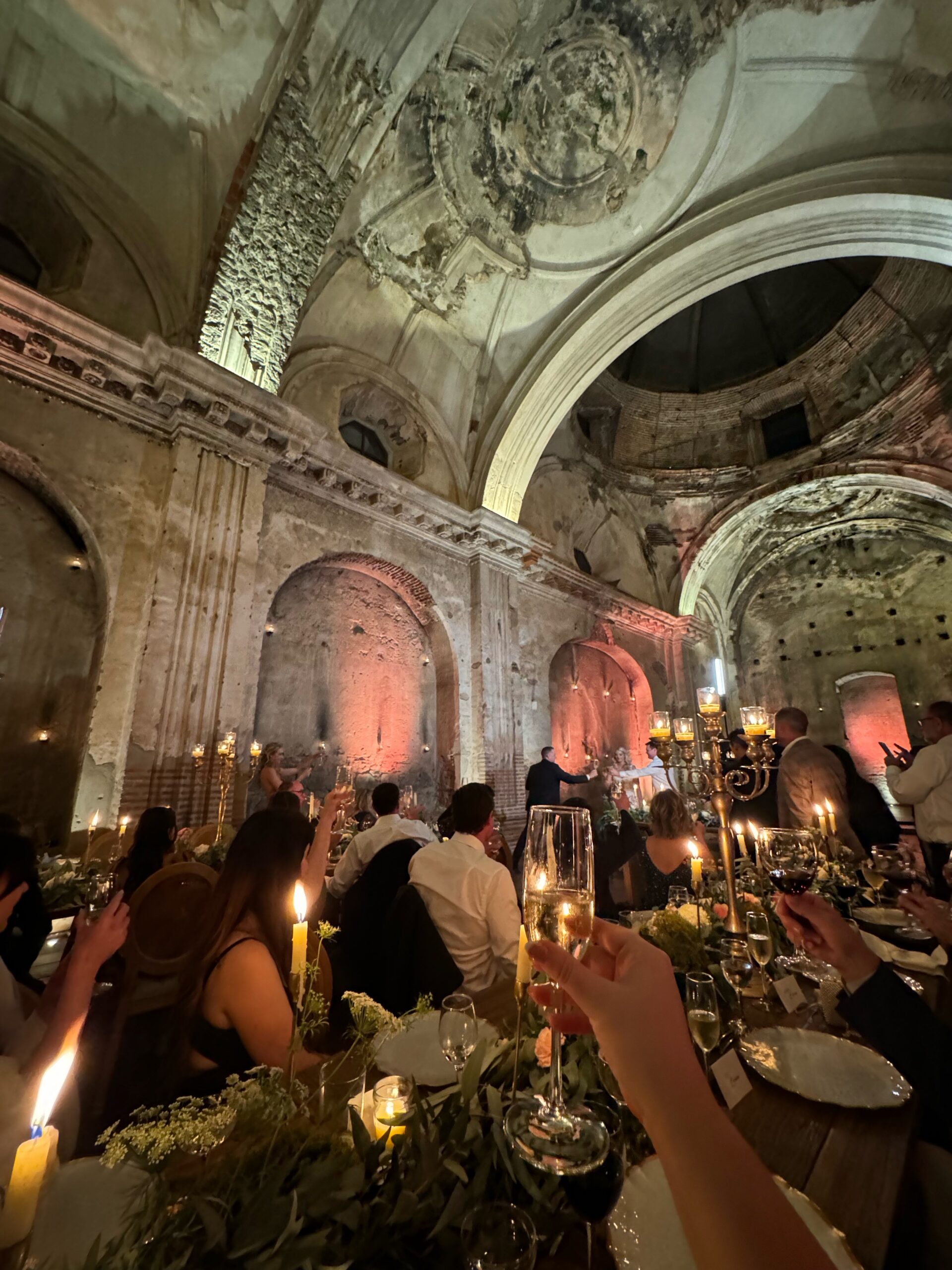 Guests toasting at a candlelit reception in a historic stone venue