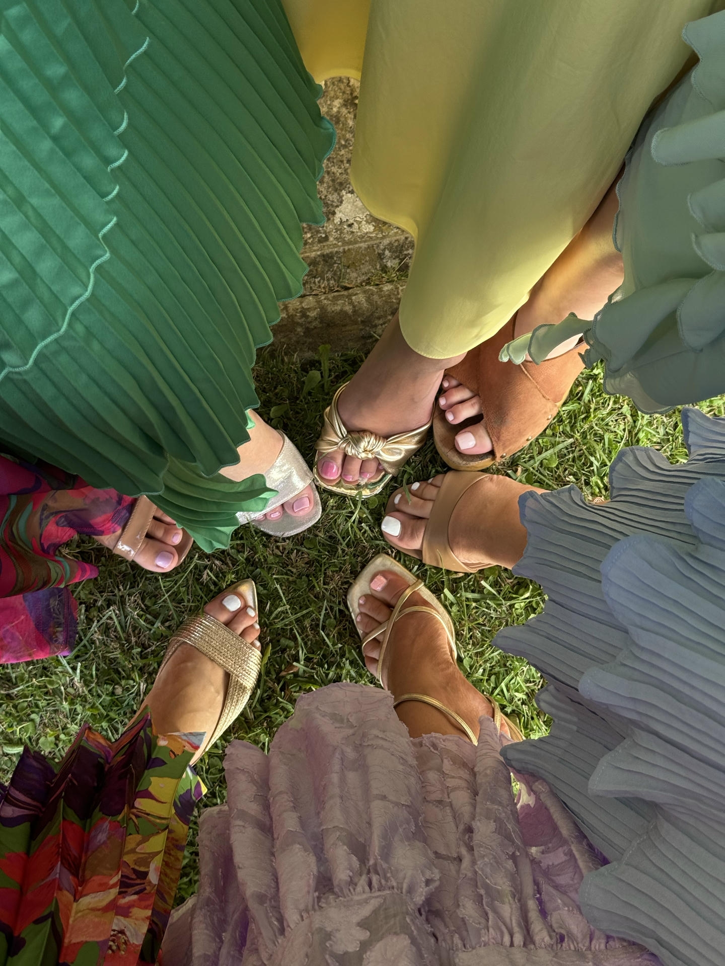 Wedding guests in colorful summer dresses and sandals on the lawn